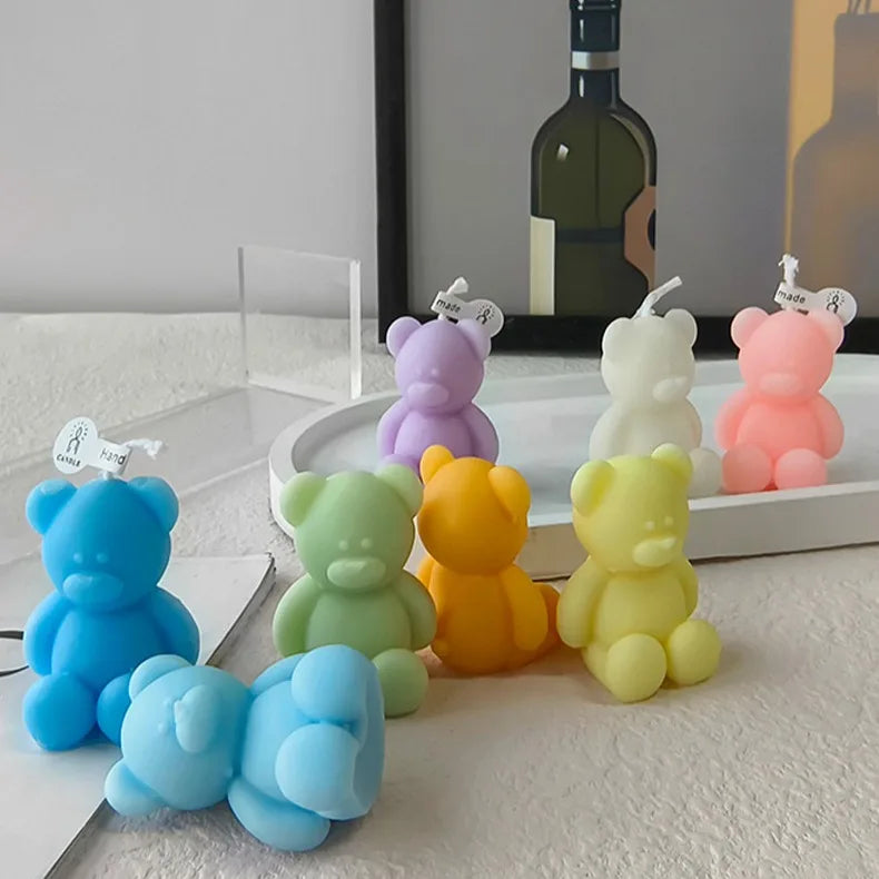 Colorful teddy bear candles arranged around a tray, with one blue bear lying in front