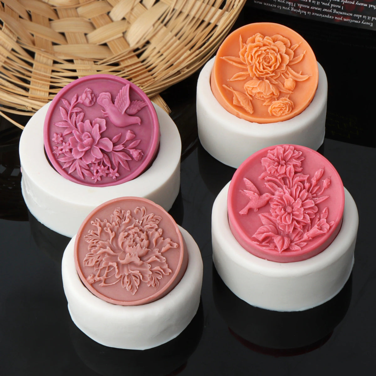 Four round flower and bird relief casting examples displayed on their white silicone molds