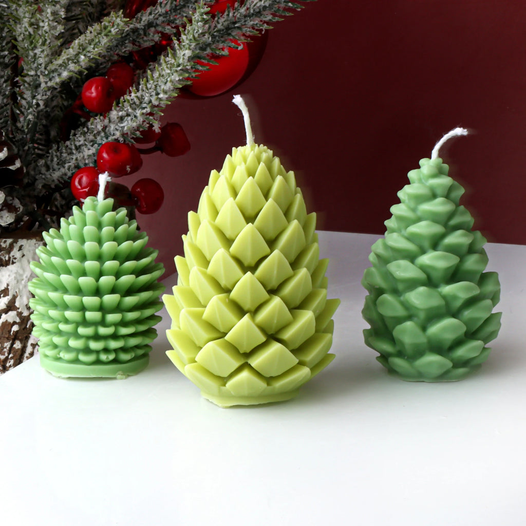 Three green pine cone-shaped candles on a white surface with a blurred decorative background.