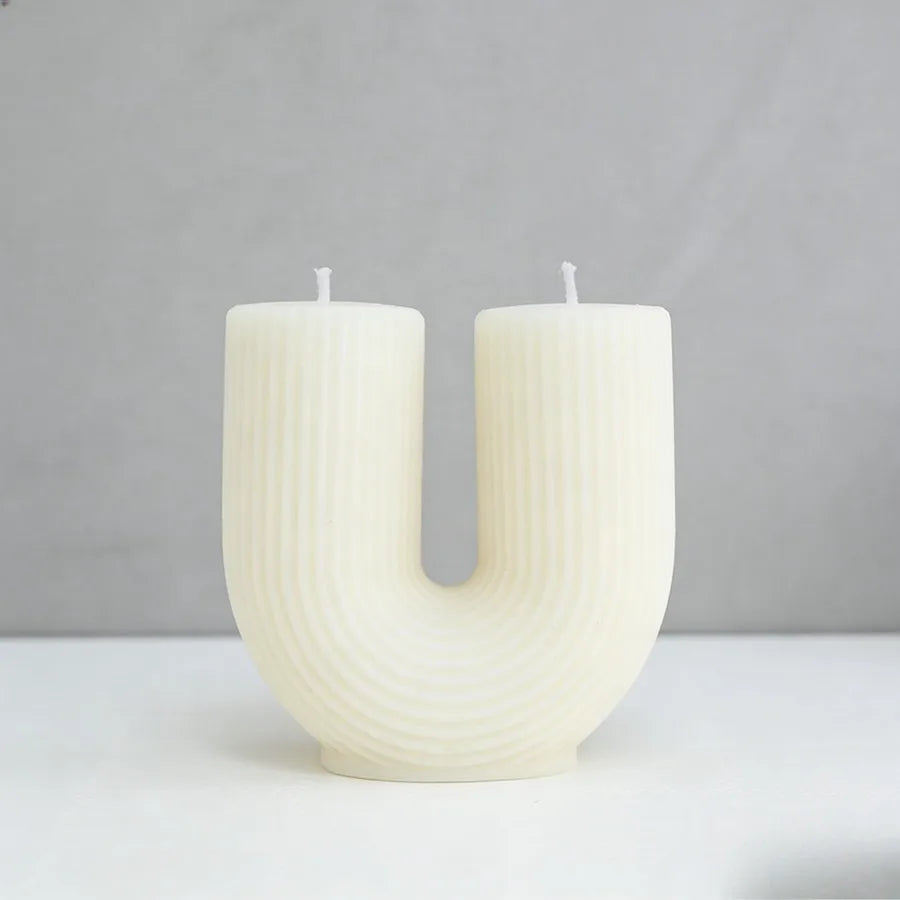 Two textured white candles on a light gray background
