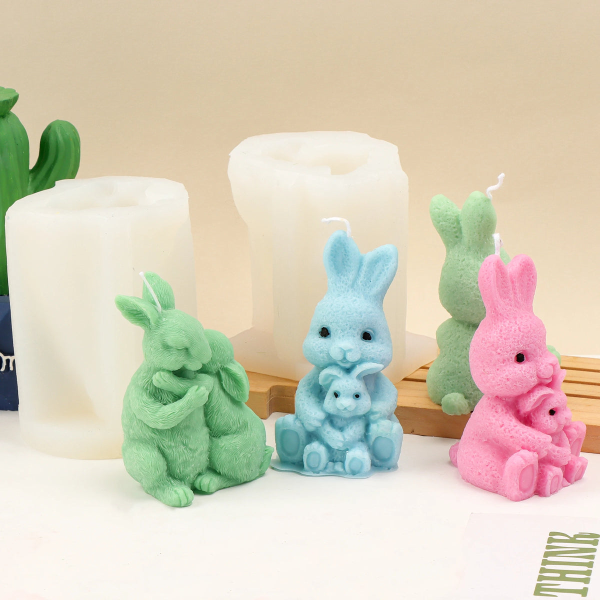 Green, blue and pink parent-and-young rabbit example candles with white silicone molds behind