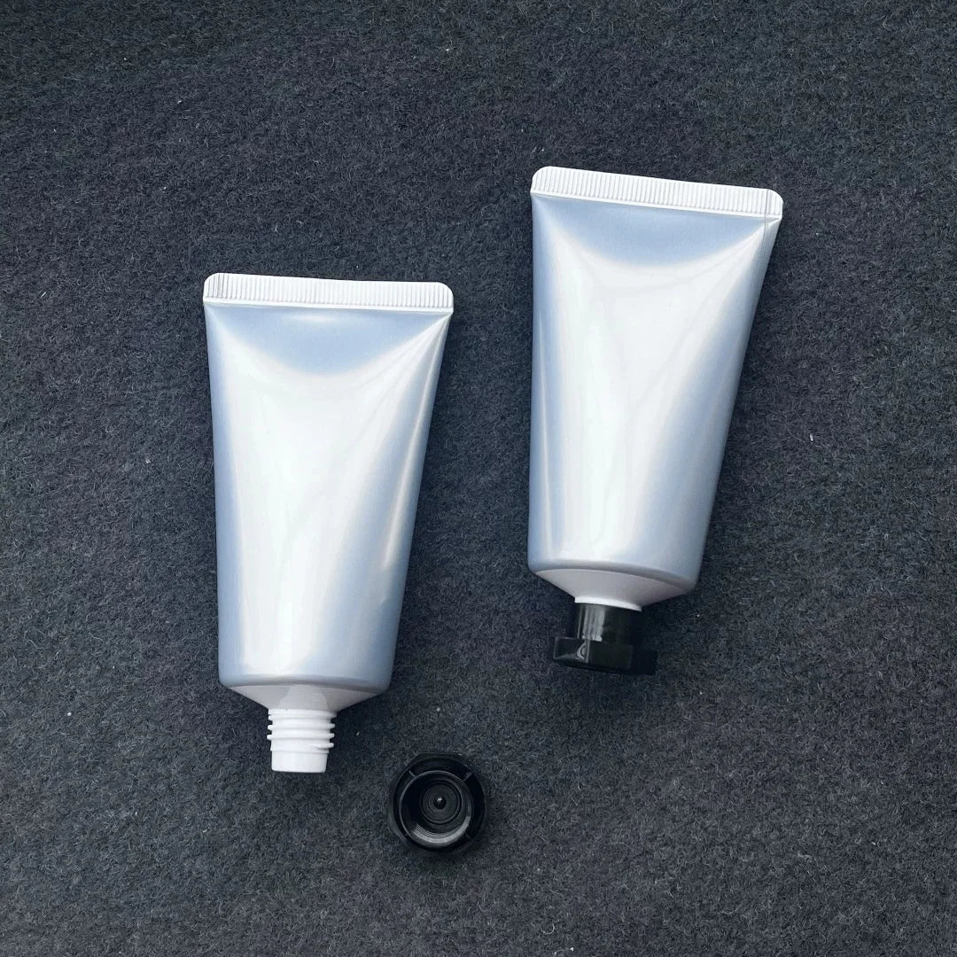Silver squeeze tubes on dark fabric, one open with its black cap removed