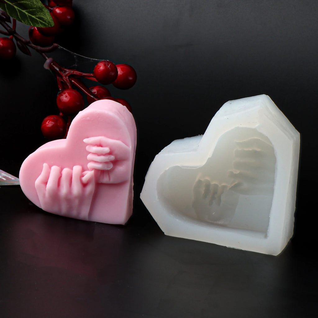 Pink heart casting with pinky-promise hands beside its white silicone mold