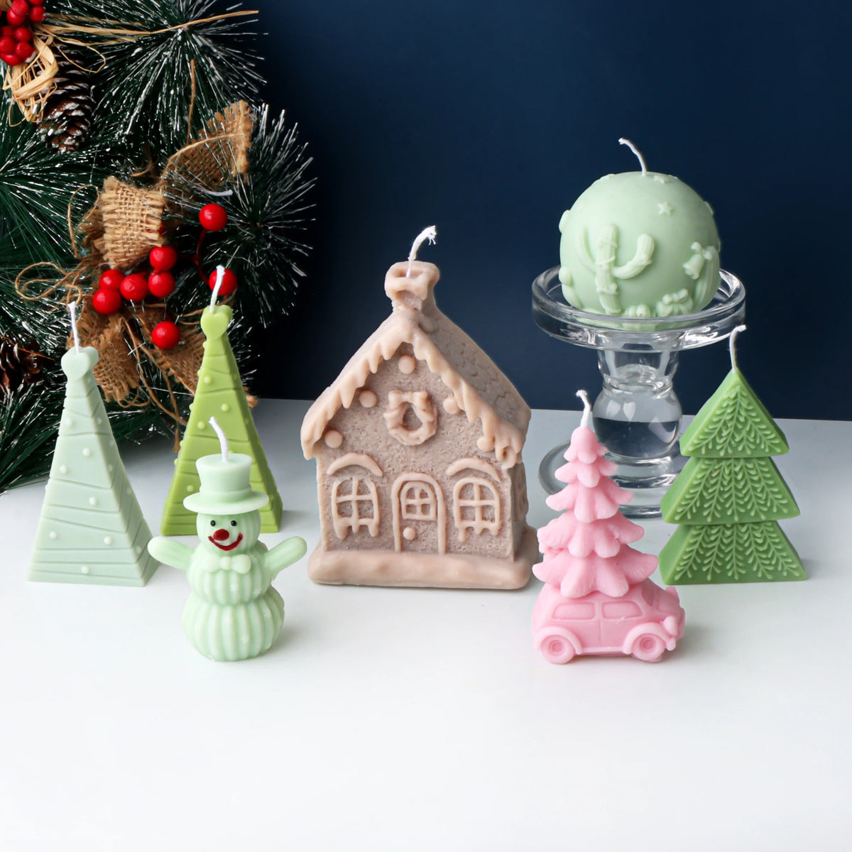 Christmas casting examples arranged before a holiday tree, including a cottage and tree-topped car
