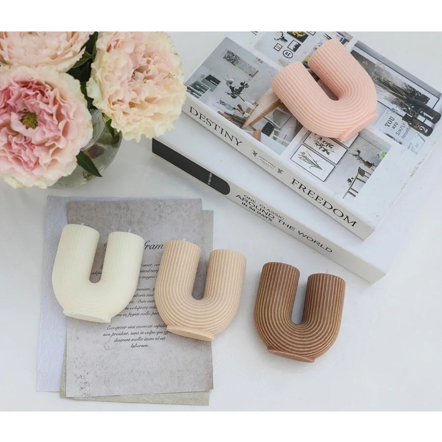 Three letter 'U' shaped objects in different colors on a surface with flowers and books.
