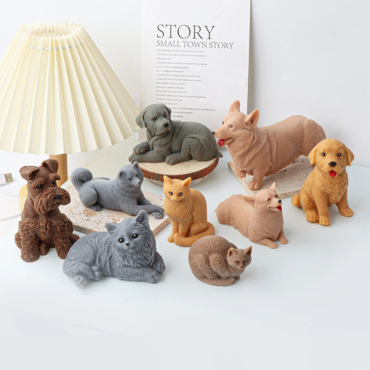 Collection of small candle mold cat and dog figurines on a white surface with a lamp in the background.
