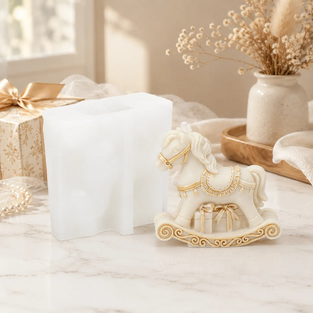 Ivory rocking-horse example candle with a gift detail beneath its saddle beside a white silicone mold