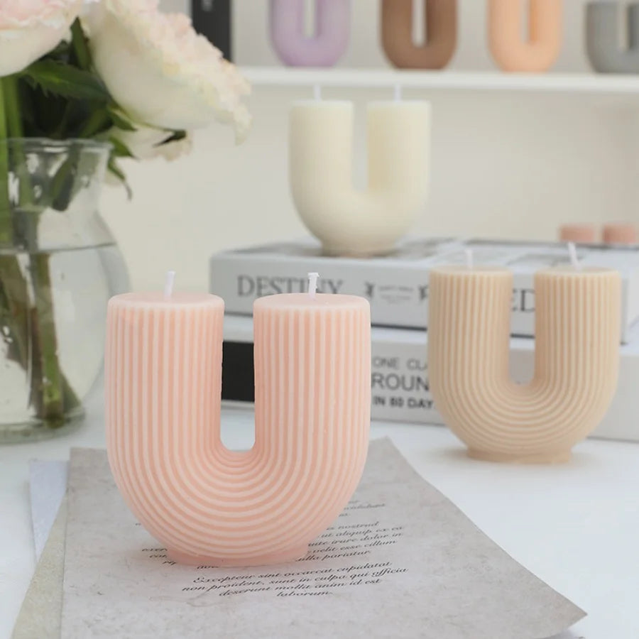 Letter 'U' shaped candles on a table with flowers and books in the background