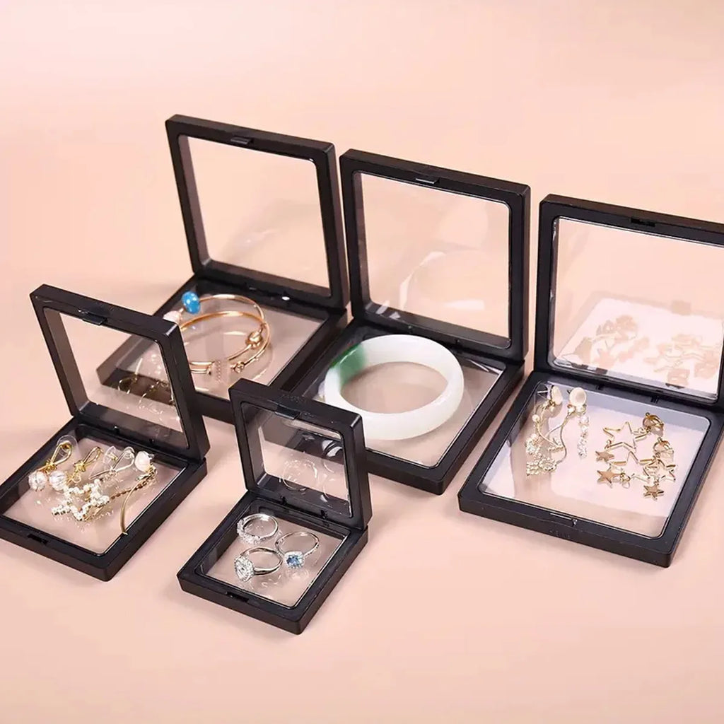 Set of jewelry in open black display cases on a beige background
