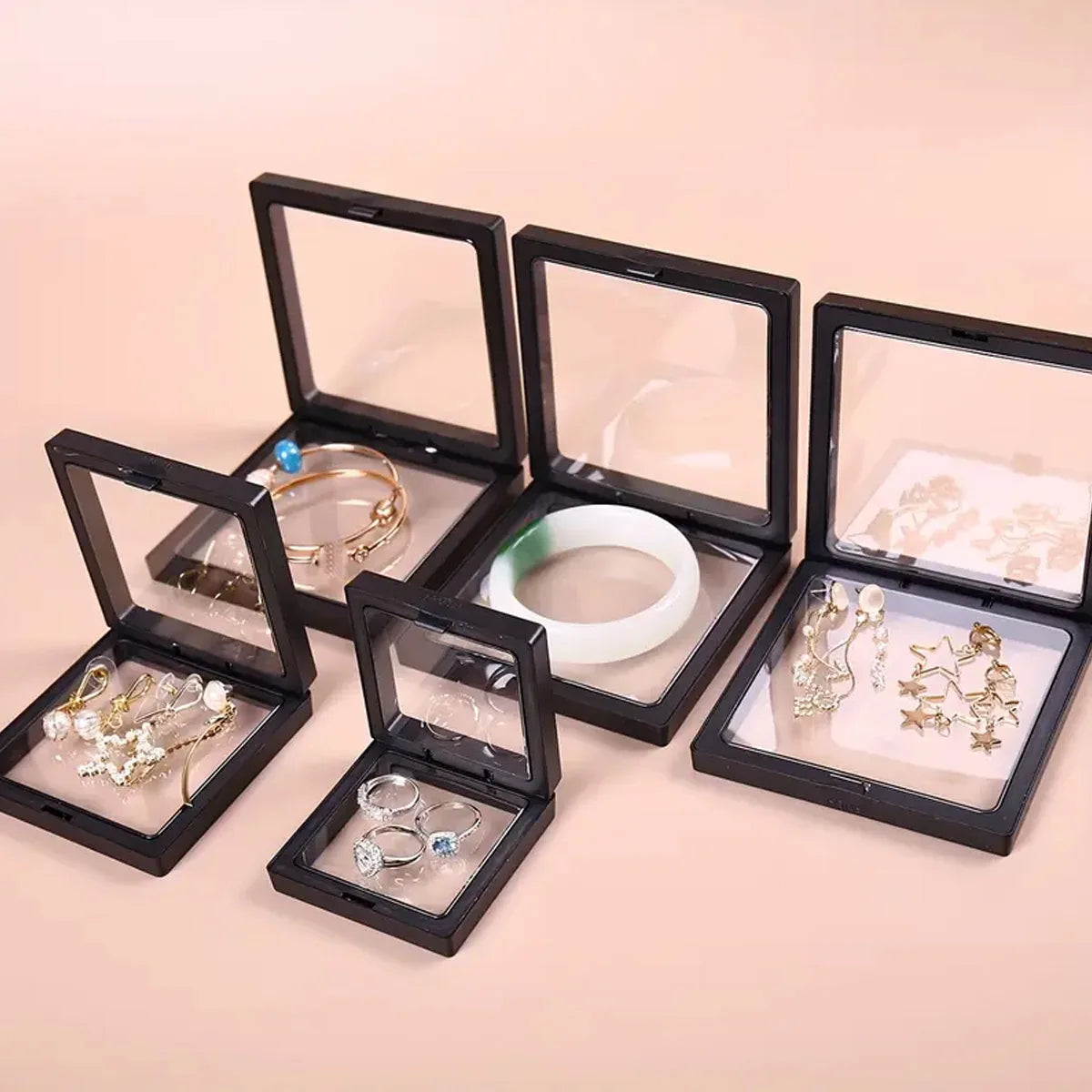Set of jewelry in open black display cases on a beige background