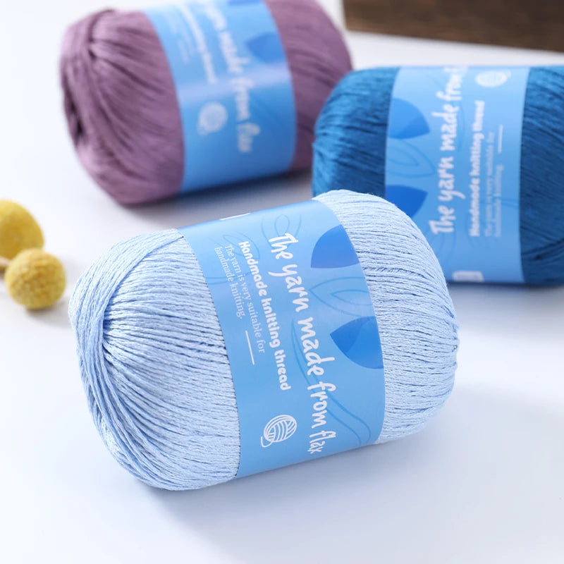 Pale blue linen lace yarn skein with blue labeling, with teal blue and purple skeins in the background.