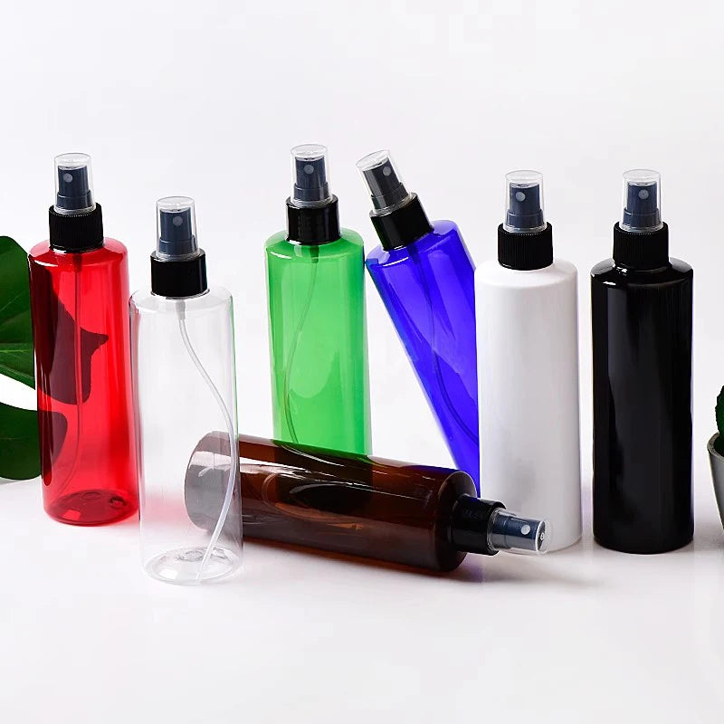 Empty spray bottles in assorted colors with black sprayers, including one brown bottle lying down