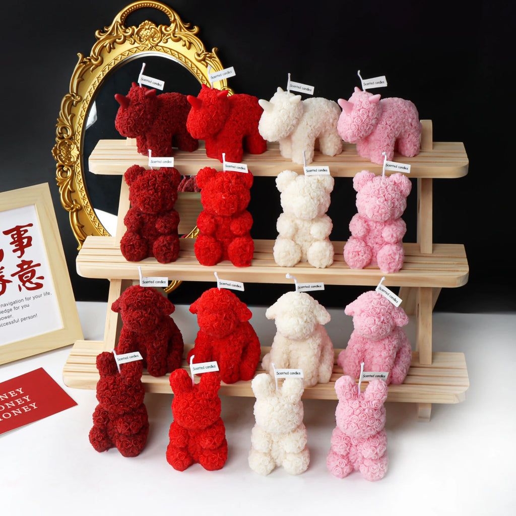 Rose-textured bear, rabbit, dog and unicorn candles in red, ivory and pink arranged on wooden shelves