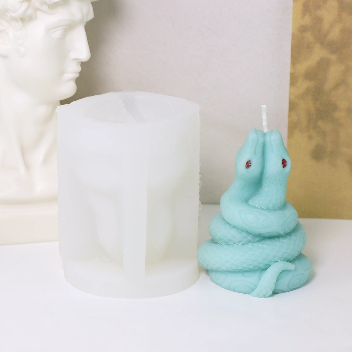 Pale turquoise raised-head coiled snake example candle beside its white silicone mold
