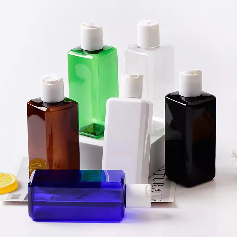 Square blue, brown, green, white, clear and black bottles with white disc-top caps