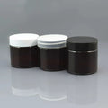 Three brown cosmetic jars with white, transparent and black lids