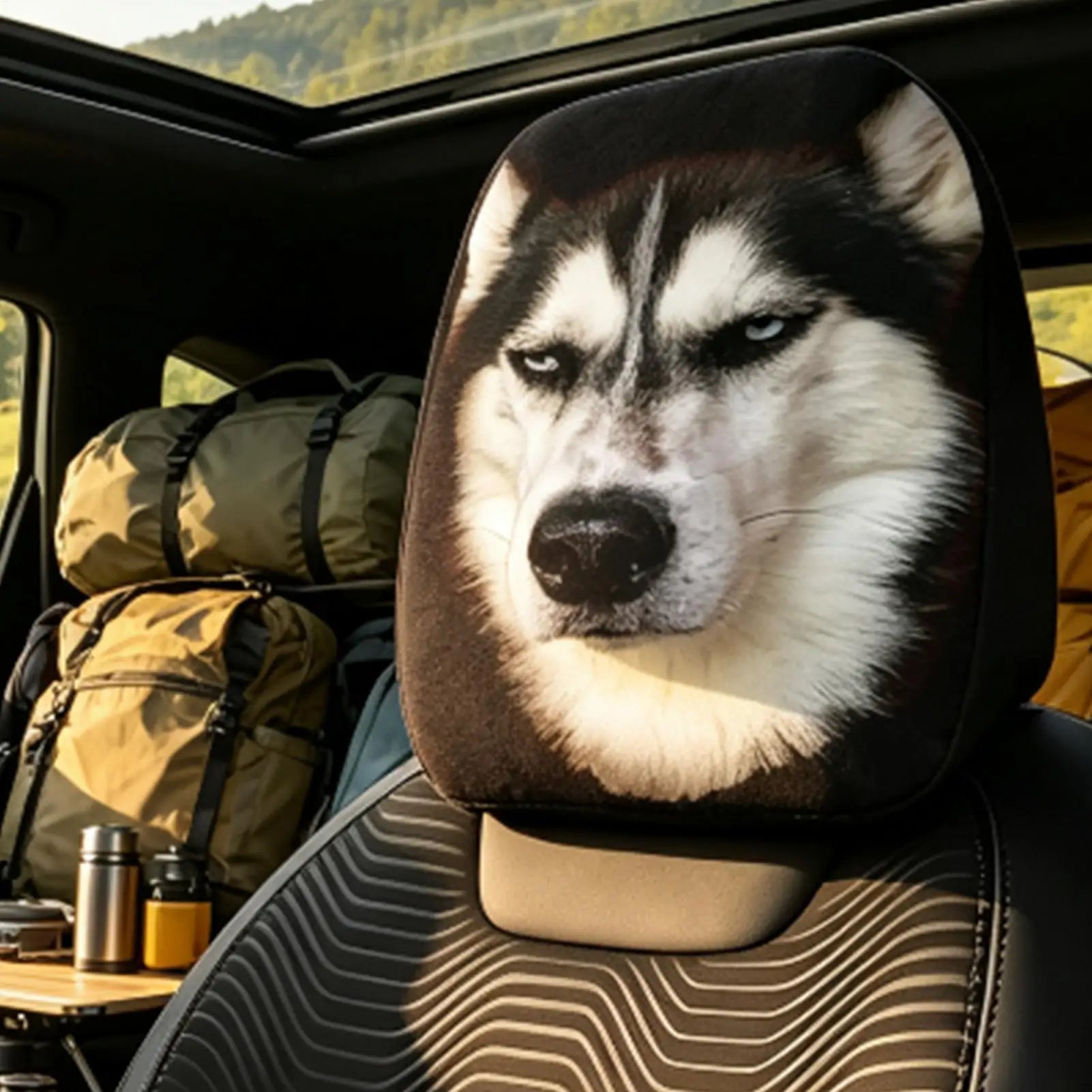 A car seat headrest cover featuring a printed husky dog face, shown installed inside a vehicle with camping gear visible in the background.