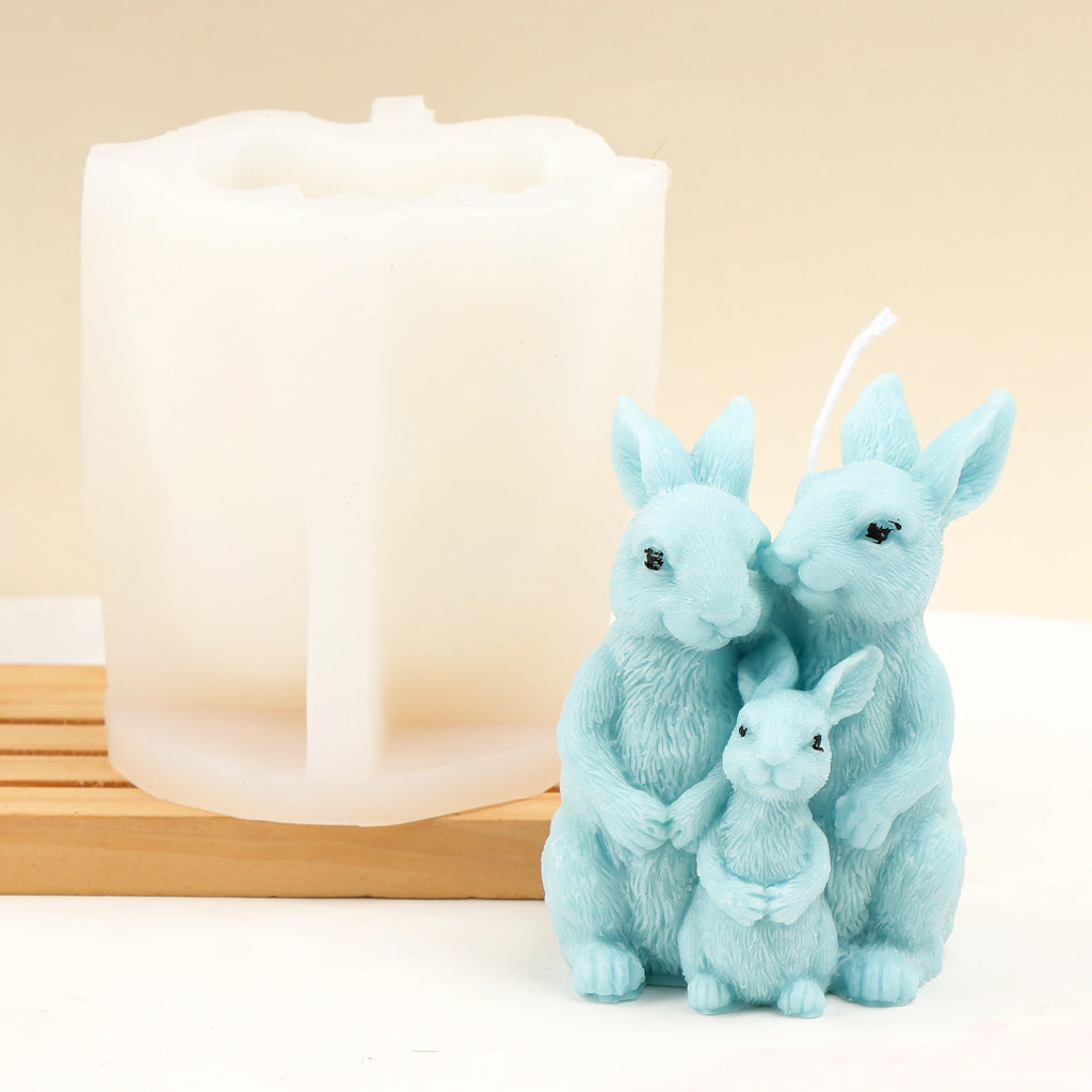 Blue three-rabbit family example candle beside its white silicone mold